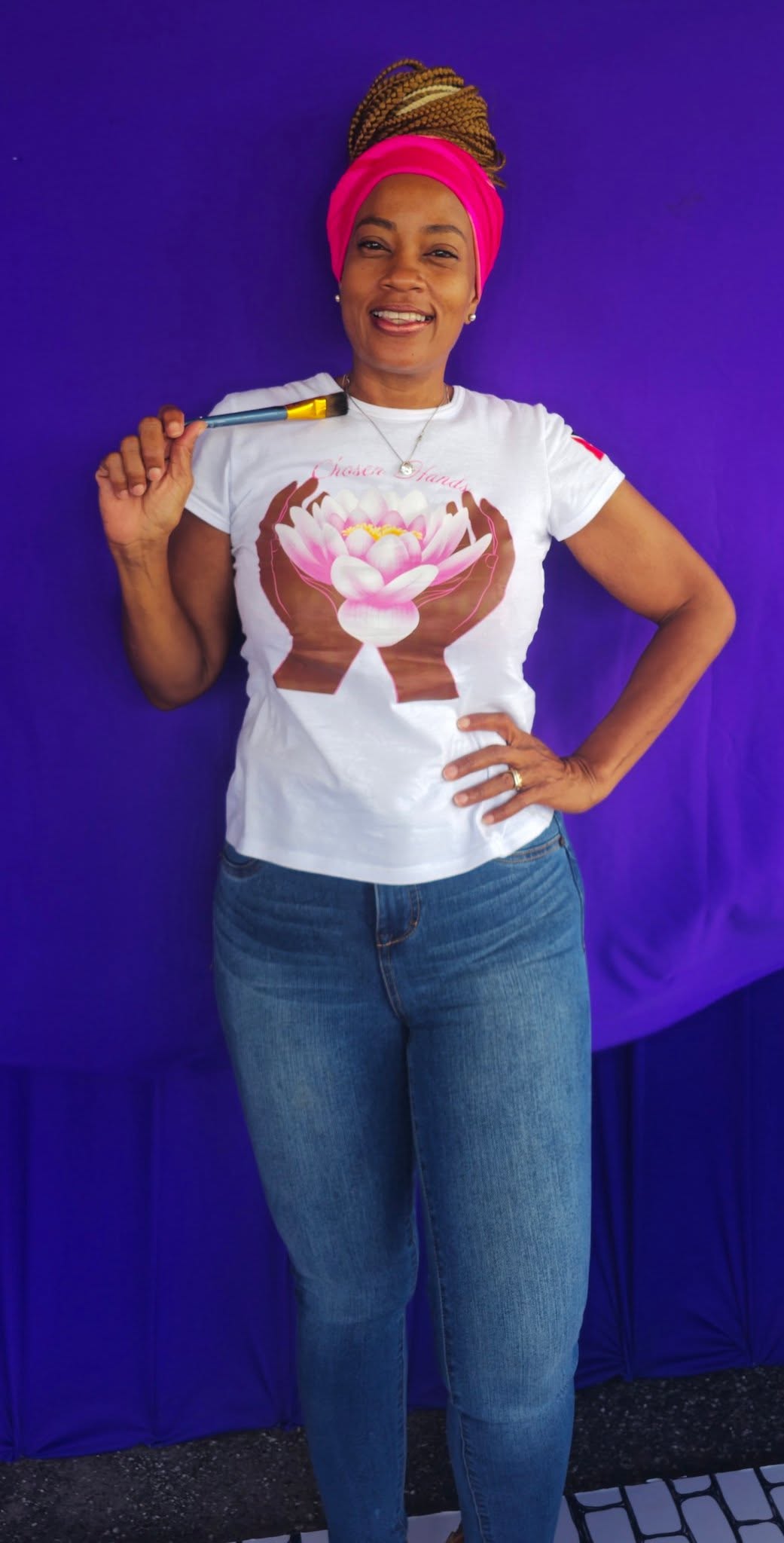 Anika wearing a Chosen Hands T-shirt and holding a paintbrush